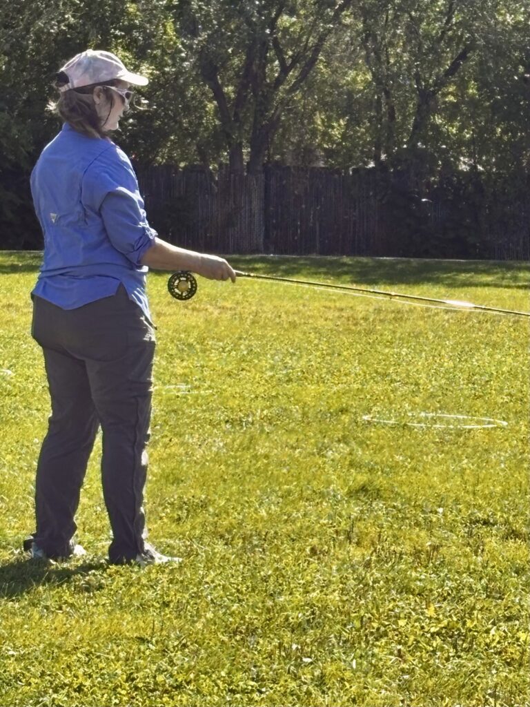 Participant practicing a fly cast on the grass at Fort Marcy Park